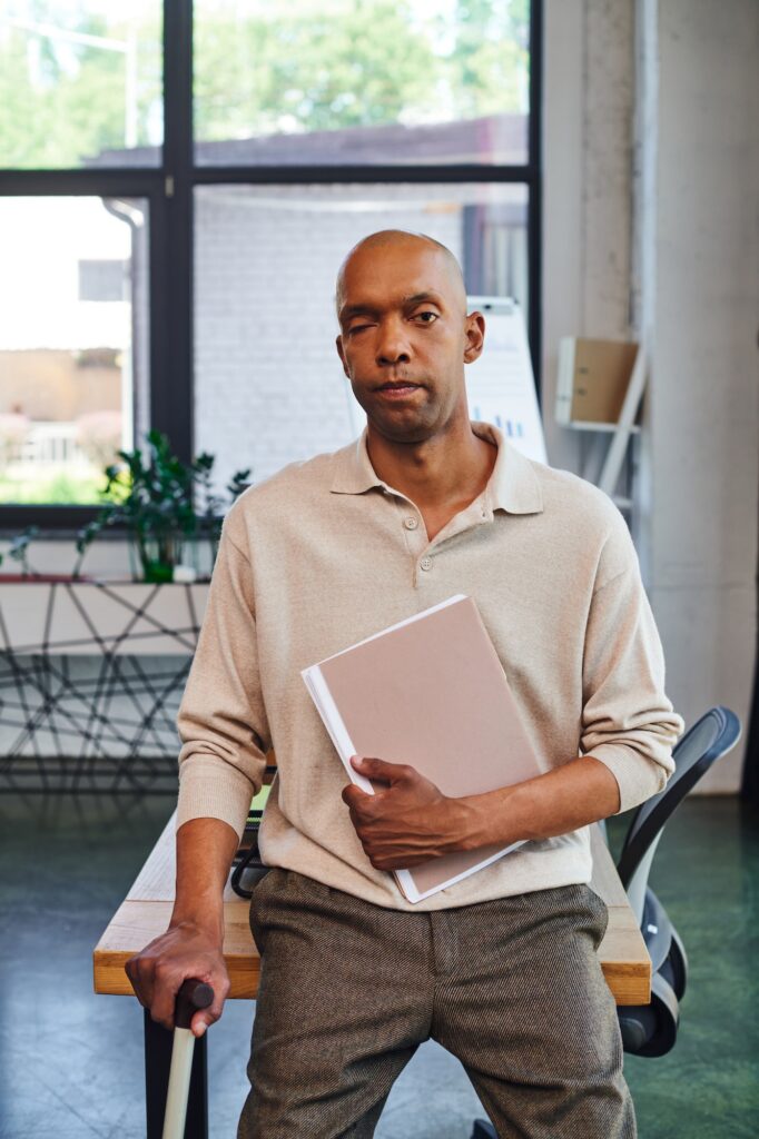 dark skinned man with myasthenia gravis disease holding folder and standing with walking cane, bold