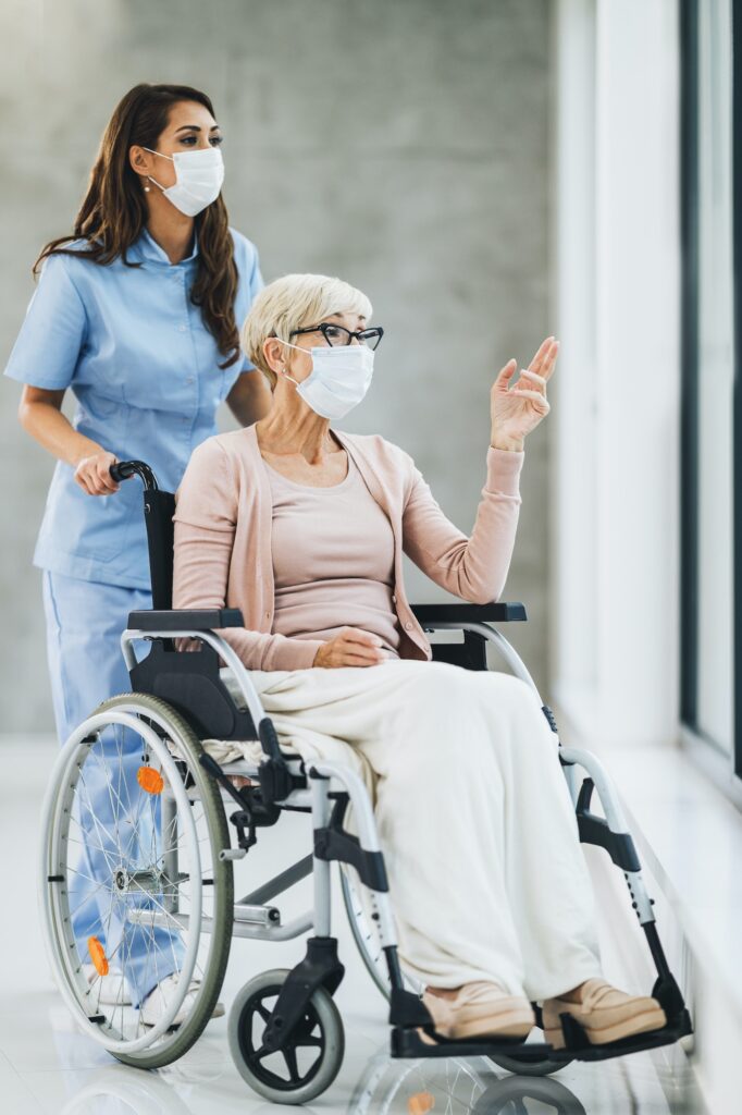 Young Caregiver Caring A Senior Female Wheelchair-Bound Patient